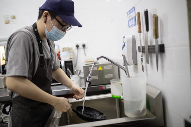 Asian Chinese owner chef washing pan in commercial kitchen.