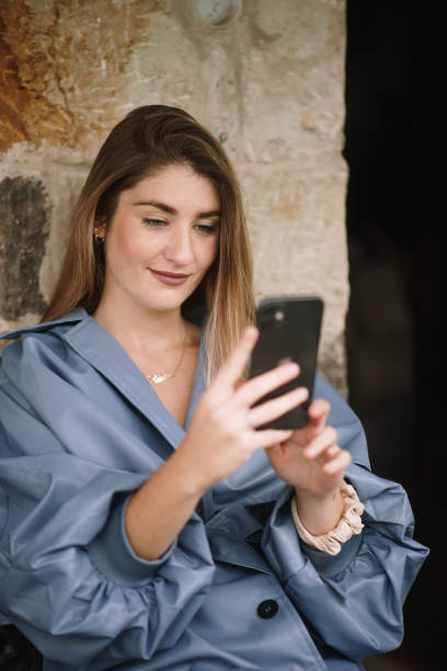 istock Young woman with raincoat using phone outdoors 1280187000