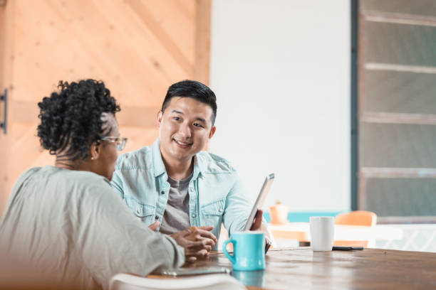 istock Man holding digital tablet smiles as date gestures and speaks 1280190361
