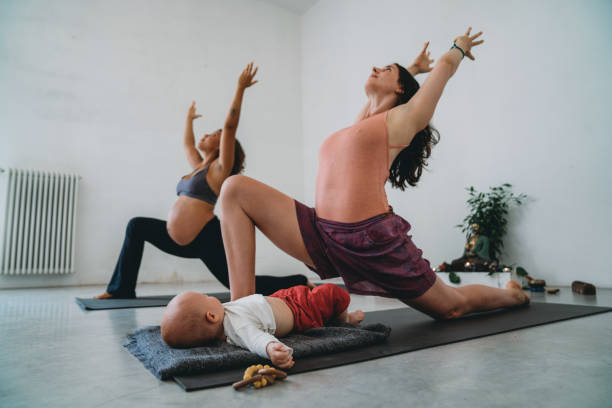 zwei freunde üben gemeinsam yoga, einer von ihnen ist schwanger und der andere hat ein kleines kind - relaxation exercise child mother human pregnancy stock-fotos und bilder