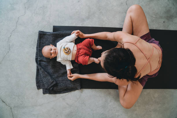 mutter mit ihrem kleinen kind während eines yoga-kurses spaß - human pregnancy exercising relaxation exercise sport stock-fotos und bilder