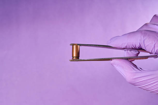 Man's gloved hand with tweezers and bullet casing Man's gloved hand with tweezers and bullet casing. russian makarov pistol pics stock pictures, royalty-free photos & images