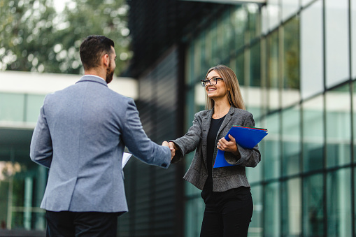 Finishing up a conversation after collaboration, handshake of two business people, male and female, after contract agreement to become a partner, collaborative teamwork