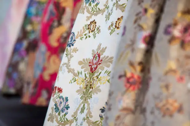 Photo of Detail of the typical dress of the fallas of Valencia. Close up photograph focused on one of the skirts with floral motifs.