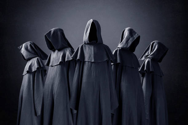Group of five scary figures in hooded cloaks in the dark stock photo