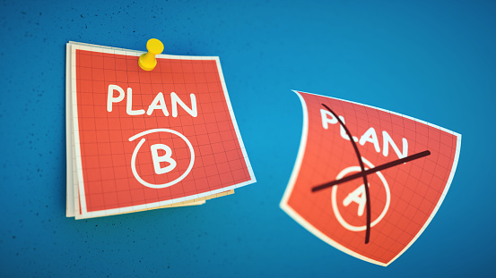 A red note with a plan B symbol circled and a plan A page crossed out and flying off.