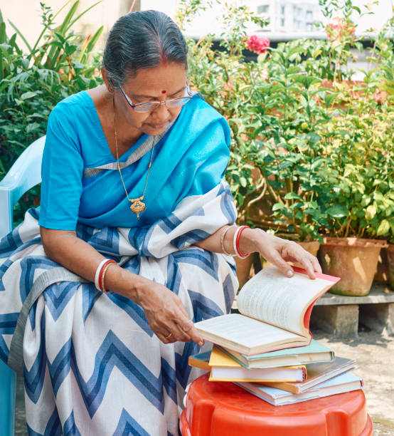 屋上で本を読む高齢のインド人女性。コルカタにて。 - traditional clothing ストックフォトと画像