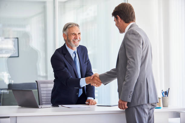 istock Businessmen shaking hands in office 1280207171
