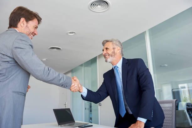 istock Businessmen shaking hands in office 1280207201