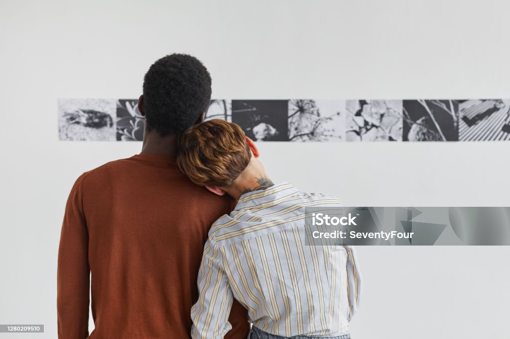 Young Couple Looking at Modern Art in Museum Back View Back view portrait of mixed-race couple embracing while looking at paintings at modern art gallery exhibition, copy space Museum Stock Photo