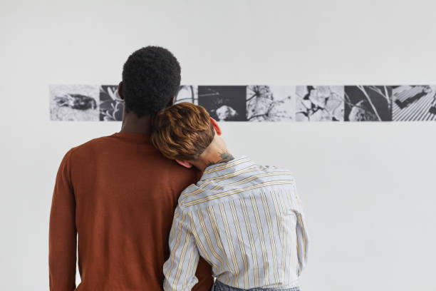Young Couple Looking at Modern Art in Museum Back View Back view portrait of mixed-race couple embracing while looking at paintings at modern art gallery exhibition, copy space showing photos stock pictures, royalty-free photos & images
