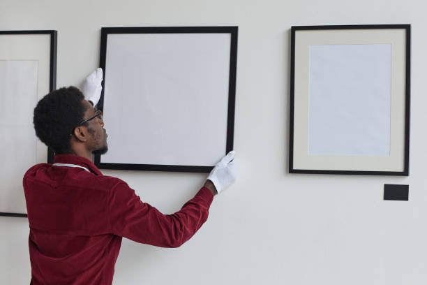 istock Young African Man Hanging Paintings on Wall in Museum 1280209544