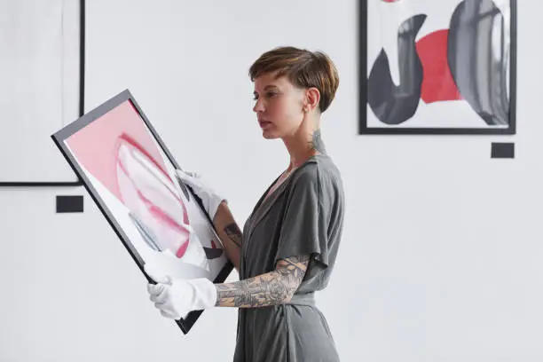 Photo of Creative Woman Holding Painting in Art Gallery