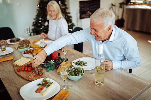 Senior couple having fun time while having lunch during celebrating December holidays