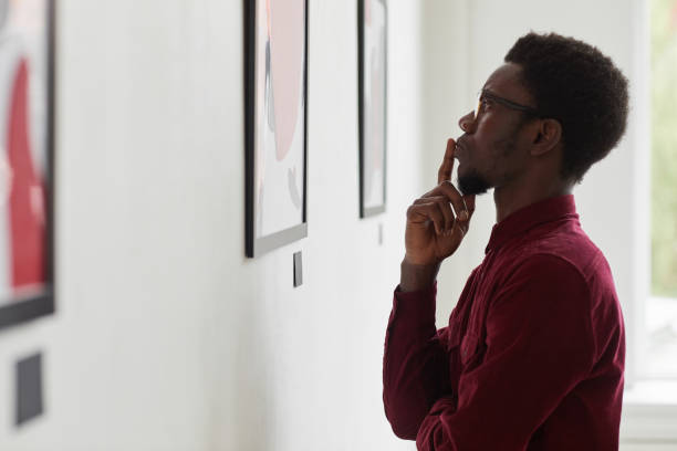 uomo afro-americano che guarda all'arte moderna - looking at pictures foto e immagini stock