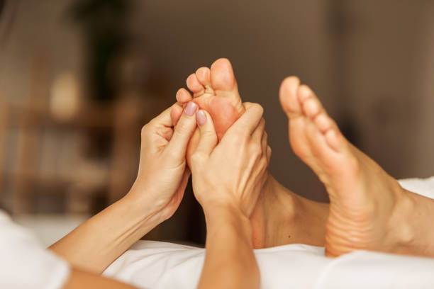 Close up of a female massage therapist's hands giving a massage to to her client's feet.
