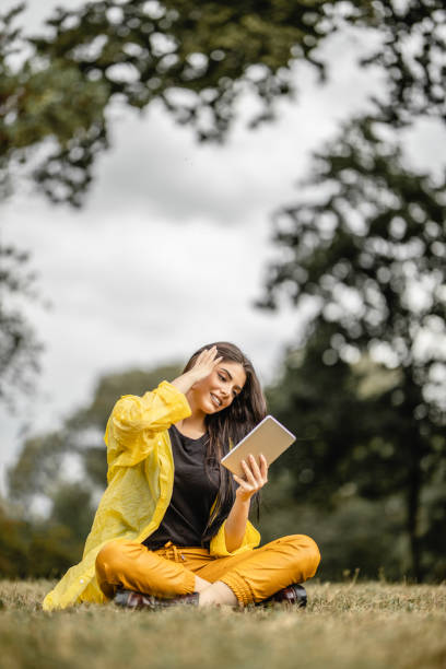 istock Beautiful woman reading e-book on digital tablet outdoors 1280211035