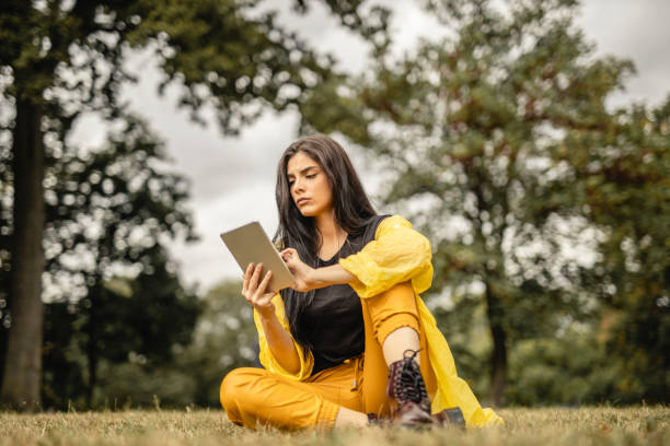 istock Beautiful woman reading e-book on digital tablet outdoors 1280211873