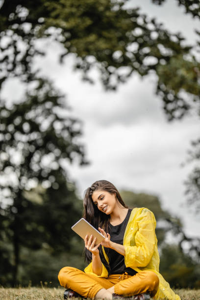 istock Beautiful woman reading e-book on digital tablet outdoors 1280212066