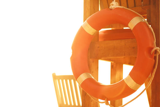 Close up of orange buoy hanging on a wooden structure during a sunny day.