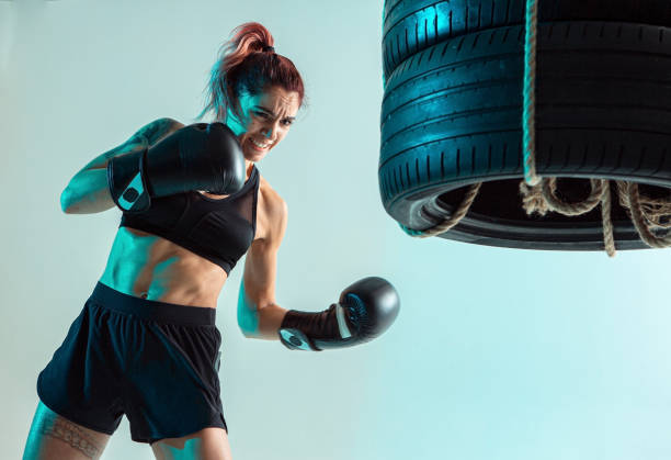 una combattente donna in guanti da boxe colpisce le gomme con la mano - undercutting foto e immagini stock