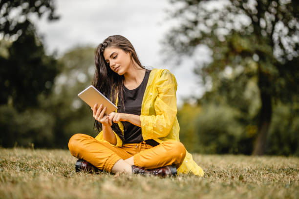 istock Beautiful woman reading e-book on digital tablet outdoors 1280215844