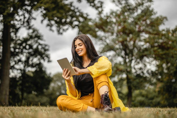 Beautiful woman reading e-book on digital tablet outdoors