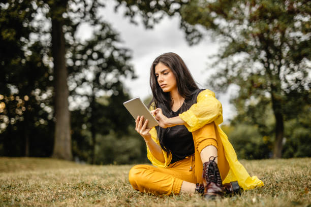 istock Beautiful woman reading e-book on digital tablet outdoors 1280215916