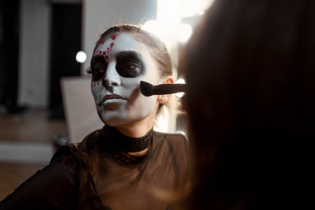 maquillaje artista pintura cara para la fiesta de la noche de halloween mirando en espejo sosteniendo lápiz - skull holding spooky horror fotografías e imágenes de stock