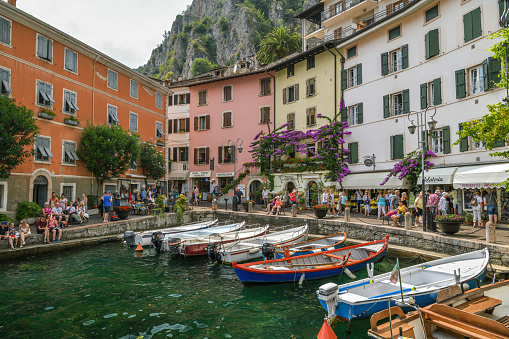 Limone Sul Garda, Italy - July 20, 2019: Tourists enjoying hot summer day in small harbor in Limone Sul Garda in Italy during July 2019