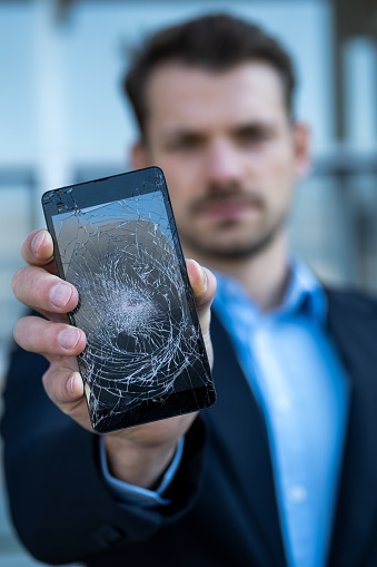 Businessman holding broken smartphone