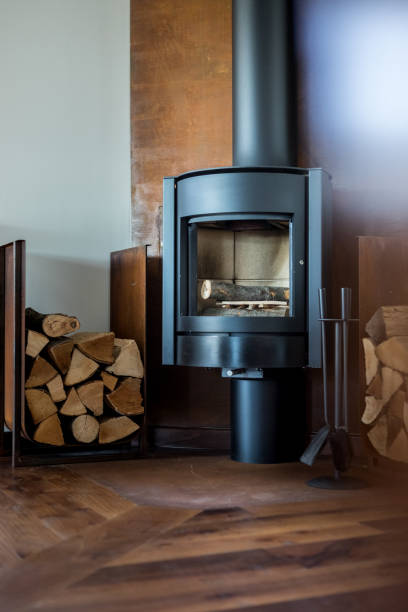 mag z kwadratu żeliwnego woodburner / współczesny piec opalany drewnem płaszcz kominkowy z pomarańczowymi płomieniami ognia płonącymi i wytwarzającymi ciepło do ogrzania pomieszczenia zamiast centralnego ogrzewania kotła gazowego, nowoczesny pie - log fire firewood fire chimney zdjęcia i obrazy z banku zdjęć