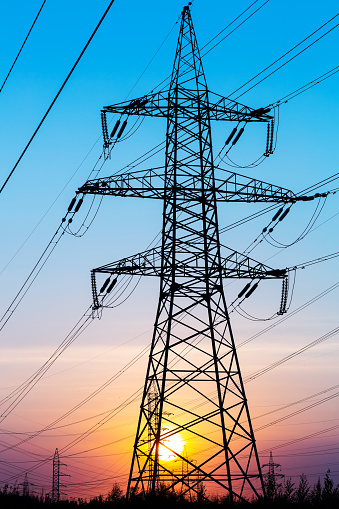 Electric power transmission lines. High voltage post. Industrial landscape. Electricity pylon at sunset sky on the background. Electric distribution station