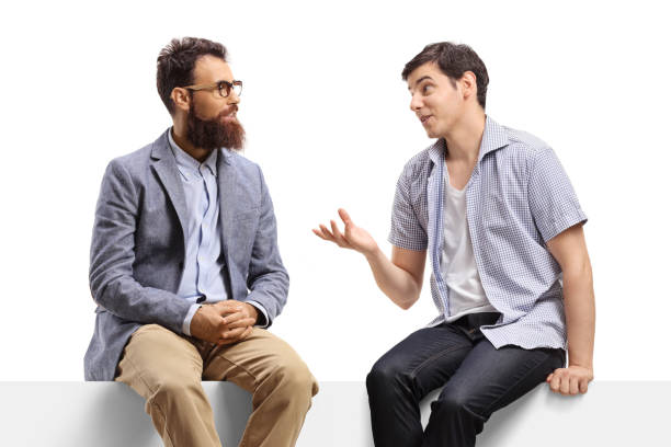 istock Two young men sitting on a banner and talking 1280221865