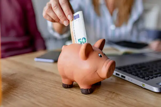 Woman's hand putting money in piggy bank