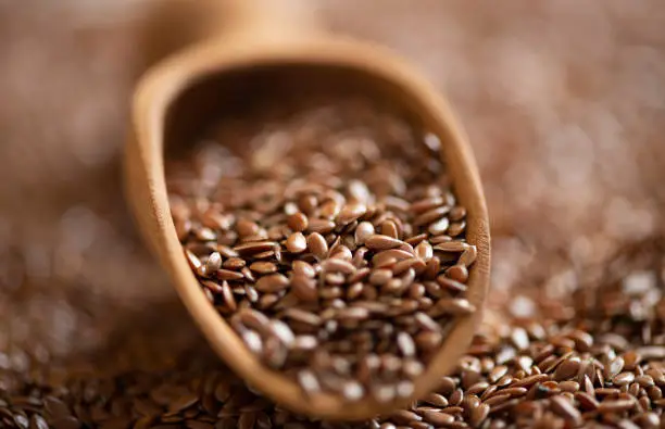 Brown flax seeds and  wooden shovel.