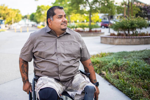 Hispanic American Veteran College Student Wheelchair A young Hispanic American Veteran college student going to class. He is a double amputee. fat mexican man pictures stock pictures, royalty-free photos & images