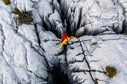 Fantastic drone point of view on a female hiking adventurist while she was crossing over a notch in the rock during her great adventure on one of the most famous travel destinations in southern Europe.