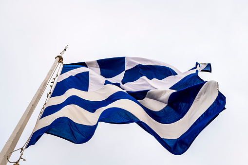 Stock photo of Greek national flag flying in sky.