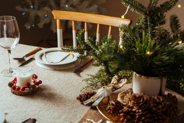 istock Homely christmas table setting, decorated with pine branches and rustic tablecloth in the living room of home tree lit background 1280239181