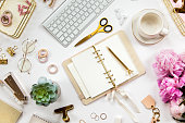 Neatly arranged office stationery with modern gadgets, devices, coffee and flowers on white desk