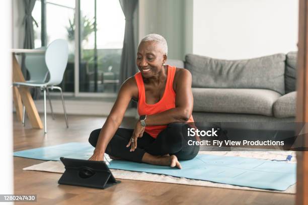 A Black Senior Woman Takes An Online Yoga Class Stock Photo - Download Image Now - Exercising, Senior Adult, Yoga