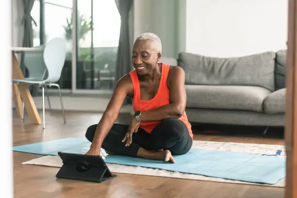 Photo of A black senior woman takes an online yoga class