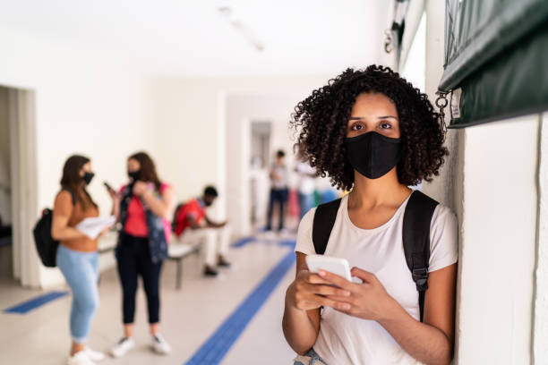 istock Portrait of a student wearing face mask using smartphone at school / university 1280249567