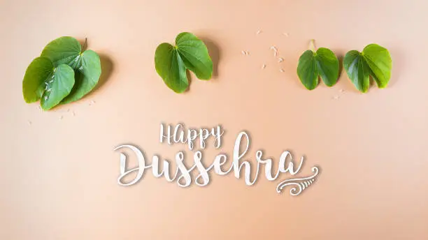 Happy Dussehra. Green leaf on orange pastel background. Dussehra Indian Festival concept.