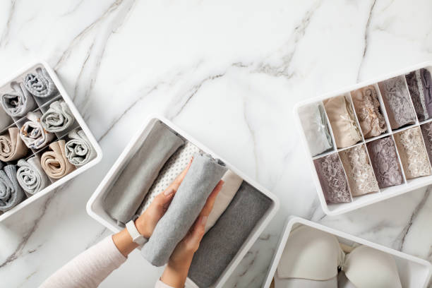 Woman hands neatly folding underwears and sorting in drawer organizers on white marble background Woman hands neatly folding underwears and sorting in drawer organizers on white marble background. Closet tidying and decluttering concept. Copyspace. Hypoallergenic fabric. Organic cotton. neat home stock pictures, royalty-free photos & images