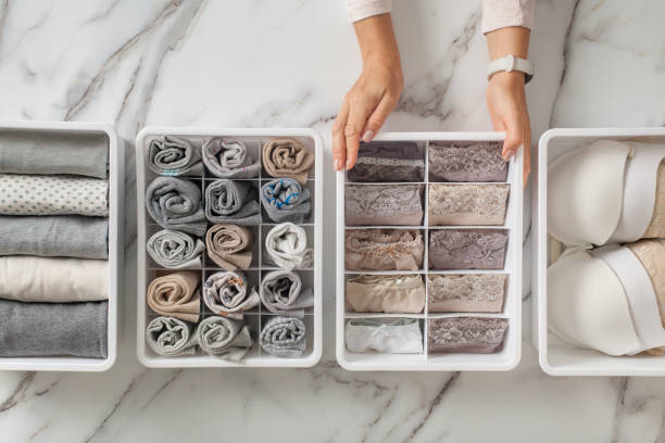 Woman hands placing organizer drawer divider with full of folded underwears and socks Woman hands placing wardrobe drawer organizers with full of folded underwears. Sock drawer with folded socks. Perfect and neatly setting of clothes. Linen drawer organization solution. Perfectionist. drawer dividers stock pictures, royalty-free photos & images