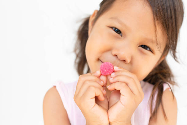 グミキャンディーを持っている幸せな子供。子供たちはビタミンをビタミン。 - nutritional supplement pill eating food ストックフォトと画像