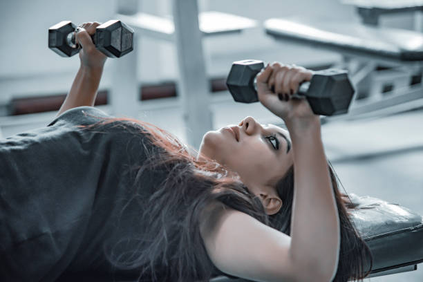 giovani donne asiatiche che lavorano in palestra - women weight bench exercising weightlifting foto e immagini stock