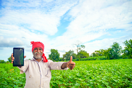 Indian farmer Showing a mobile screen at agriculture field